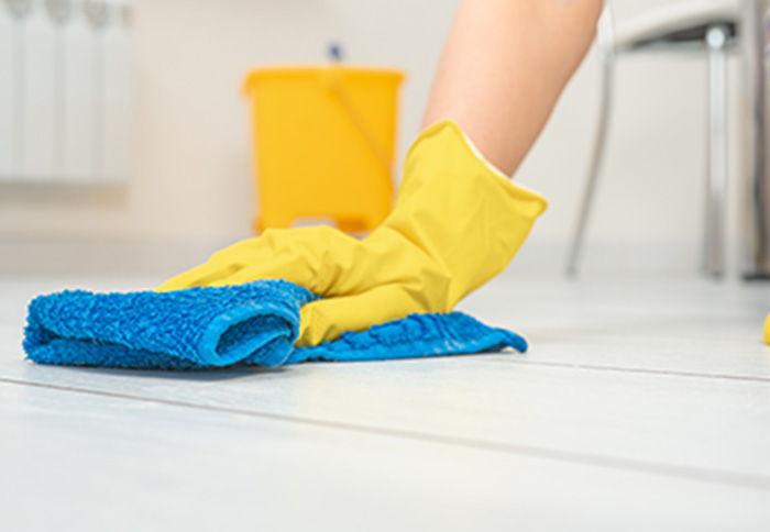 Professional cleaner washing white floor with blue cloth