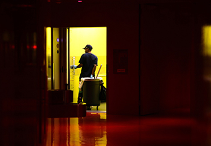 Cleaning person pulling trash can using elevator