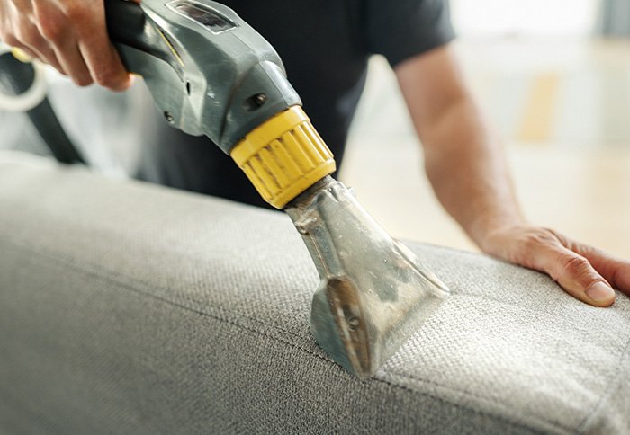 Cleaning worker performing deep clean of sofa cushions